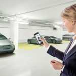 Mujer en un parking abriendo su coche a través del móvil