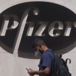 Un hombre pasa por delante del logo de la compañía farmacéutica Pfizer. Foto: REUTERS/Carlo Allegri