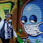 Imagen de archivo. Una mujer con mascarilla camina frente a un graffiti luego de que autoridades de salud revirtieran las medidas de reapertura tras el aumento de casos de coronavirus en San José, Costa Rica. 13 de julio de 2020. REUTERS/Juan Carlos Ulate