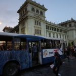 Manifestantes se acercan a un autobús incendiado por manifestantes frente al Palacio Nacional para exigir la renuncia del presidente Alejandro Giammattei, en la Ciudad de Guatemala, el sábado 28 de noviembre de 2020. (Foto AP/Moisés Castillo)