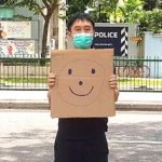 Jolovan Wham usa una máscara y sostiene una cartulina con un dibujo de una cara sonriente en Singapur, el 28 de marzo de 2020 (Jolovan Wham / REUTERS)
