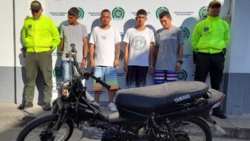 En la foto aparecen cuatro presuntos integrantes de ‘Los Chatarreros’, acompañados a sus lados de dos uniformados de la Policía Nacional. Delante de ellos se ve una motocicleta incautada y detrás de ellos hay un pendón institucional de la Policía Nacional. 