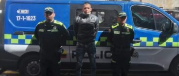 En la fotografía se observa al capturado junto a dos agentes de la Policía Nacional.   En la parte superior se observa una radiopatrulla de la Policía